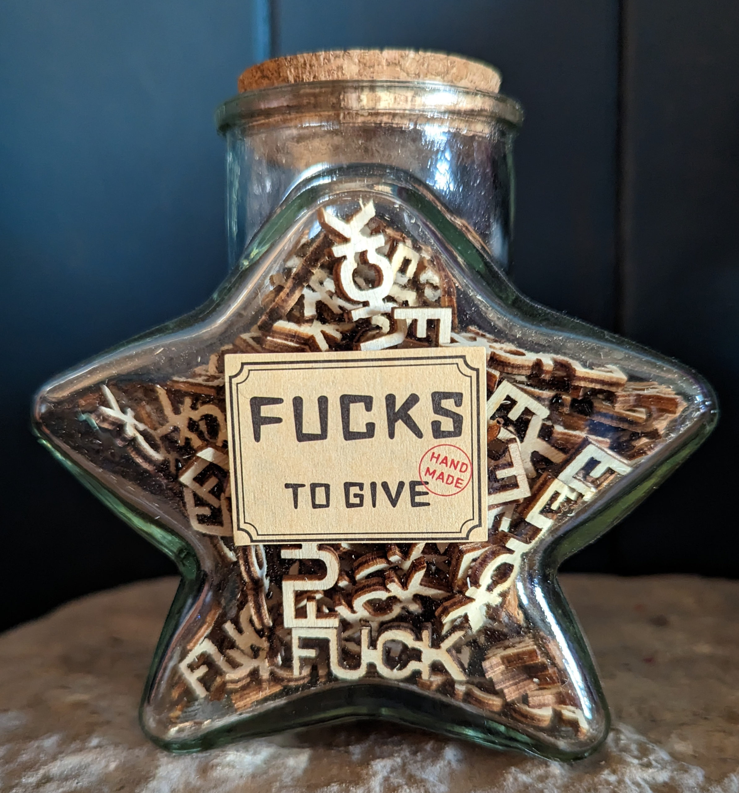 a star shaped jar containing wood pieces cut into the word fuck
